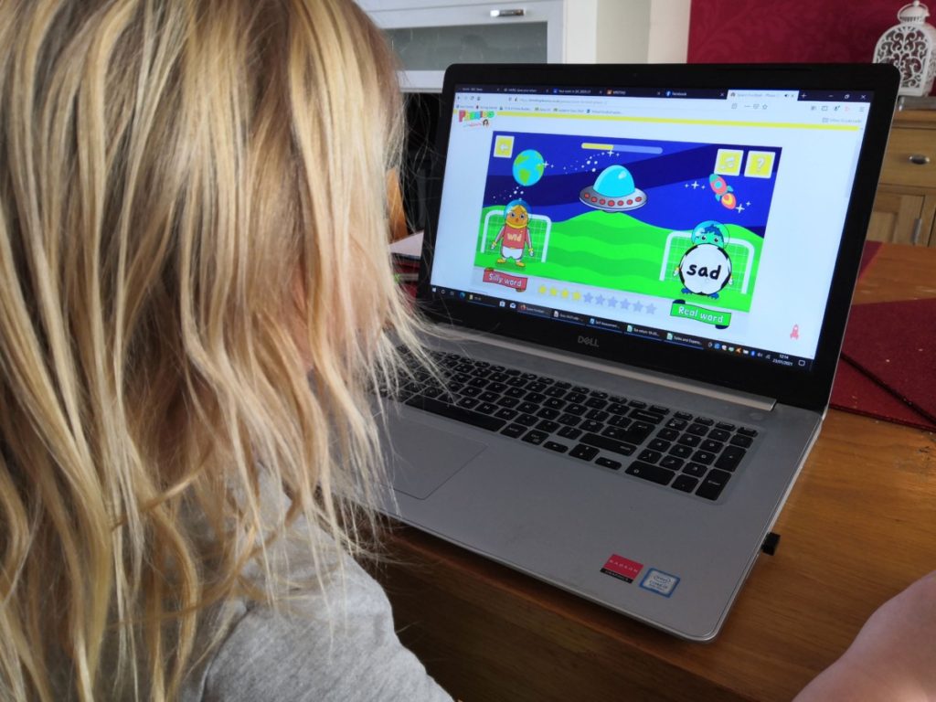 Girl playing phonics game on laptop